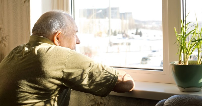 older man watching out of window